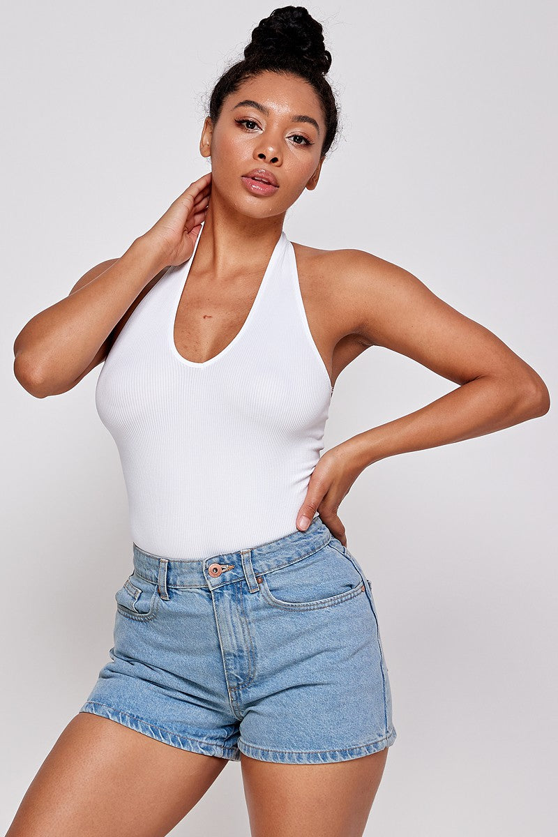 Woman wearing a white halter neck bodysuit top and denim shorts 