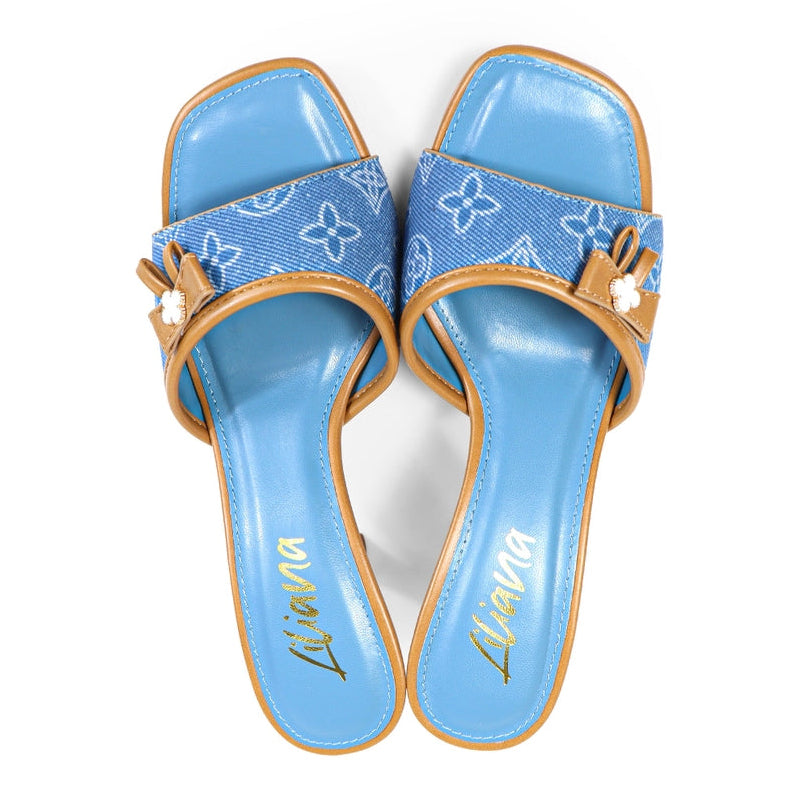 Pair of blue sandals with clover flower pattern and faux leather brown straps on a white background