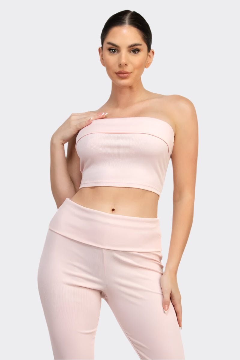 Woman wearing a pink strapless top and pants on a white background