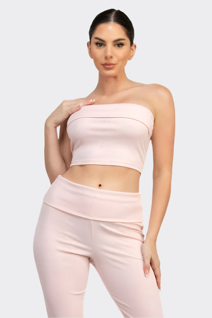 Woman wearing a pink strapless top and pants on a white background