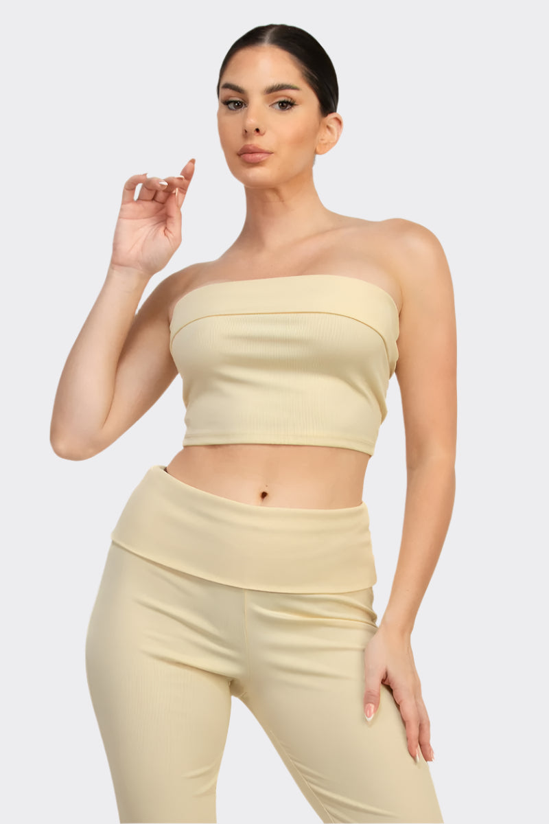 Woman wearing a light yellow strapless top and pants on a white background