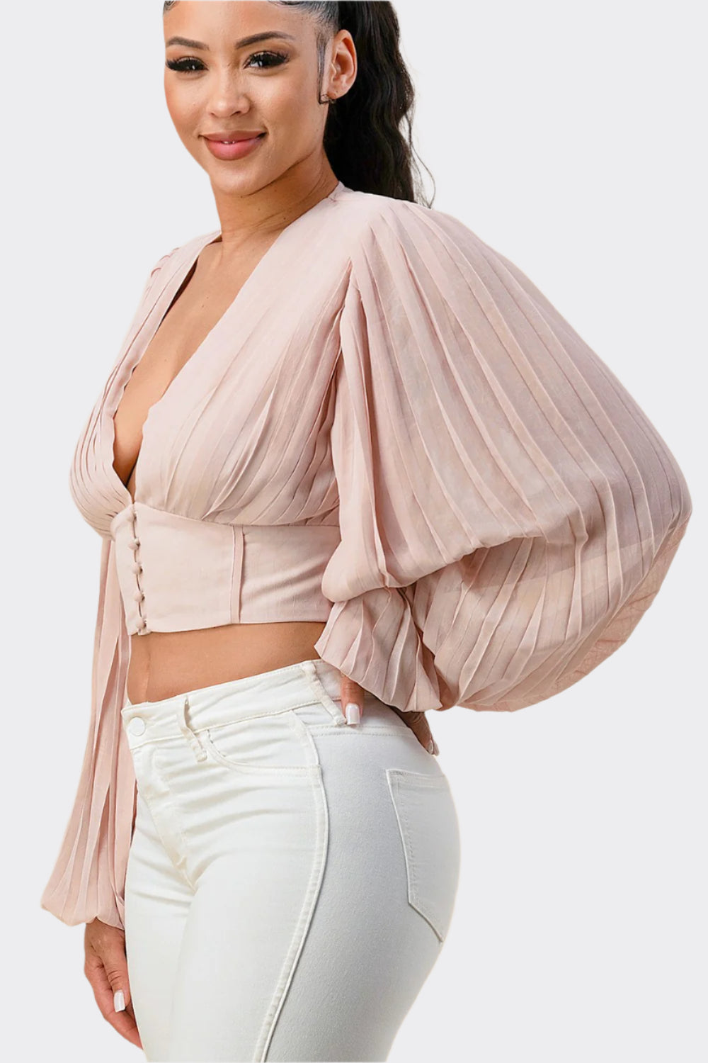 Woman wearing a light pink blouse with balloon sleeves against a beige background
